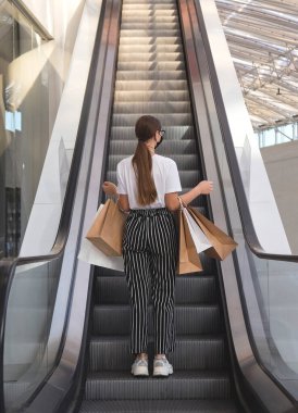 Alışveriş merkezinde gözlüklü ve koruyucu maskeli bir kız.