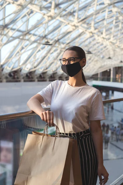 Meisje met bril en een beschermend masker in een winkelcentrum met aankopen — Stockfoto