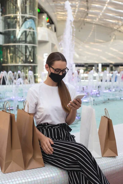 Meisje met bril en een beschermend masker in een winkelcentrum met aankopen — Stockfoto