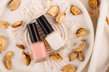Vegan nude nail polish on natural background of wood and dry plants clipart