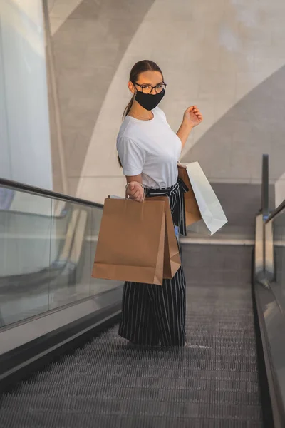 Meisje met bril en een beschermend masker in een winkelcentrum met aankopen — Stockfoto