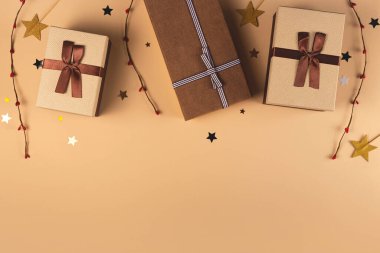 Süslemeler arasında tarafsız bir arkaplanda üç Noel hediyesi kutusu