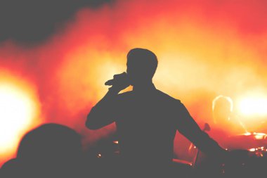 İnsan aydınlık pop-rock konserinde sahne önünde siluetleri. El jest boynuzları. Şok edici. Bir kulüpte parti