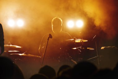 İnsan aydınlık pop-rock konserinde sahne önünde siluetleri. El jest boynuzları. Şok edici. Bir kulüpte parti