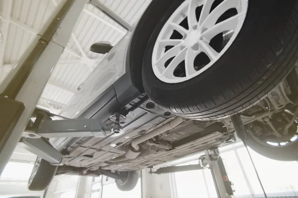 Car on a wheel alignment lift in auto service. Diagnosis of the chassis of the car raised at the elevator. toning