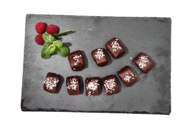 Tatlı çikolata tatlılar Hindistancevizi talaşı ve kırmızı ahududu, ortaya konulan bir grafit gemide serpilir beyaz bir arka plan üzerinde izole. Üstten görünüm