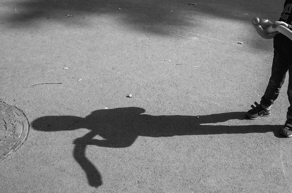 Shadow of a lonely boy with a balloon on the asphalt in monochrome