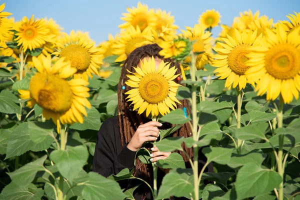 Schüchternes Mädchen verbarg ihr Gesicht hinter einer Sonnenblumenblume — Stockfoto