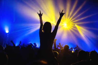 Kız kulüpte bir rock grubunun bir konser sırasında boynuz işareti gösterir. Konser sırasında kişilik bir kalabalık. İki parmak ile bir el. Konserde siluet.