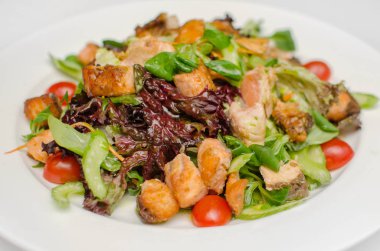 yeşil ve beyaz tabakta domates ile kızarmış kırmızı balık salatası