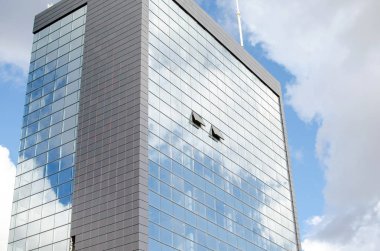 Modern gökdelen gökyüzü ve bulutlar yansıtan açık bir pencere ile yapılmış cam ve çelik