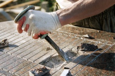 mermer bir levha üzerinde çekiç ve keski ile çalışan eldivenlerde yakın çekim taş kesici. Toz içinde iş kıyafetleri giymiş bir adam. özenli çalışma