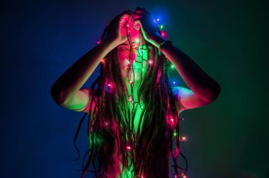 dreadlocks ile kız yüzünü önünde parlak bir çok renkli garland tutar