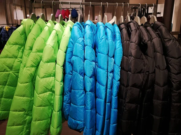 fashionable raincoats in bright colors on a stand for sale in a clothing store