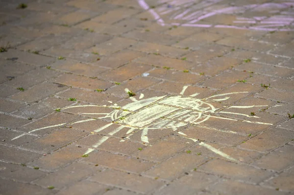 child painted the sun on the pavement with yellow chalk. children\'s drawings on the tiles.