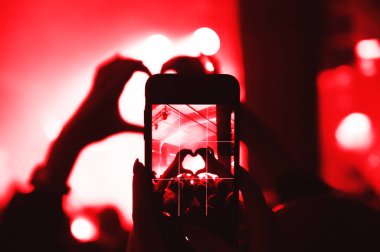 Konserde kalabalıktan gelen elleri olan, kalp yapan ve sanatçılara aşk gönderen akıllı telefon ekranı. Müzik gruplarının hayranıyım. festival atmosferi