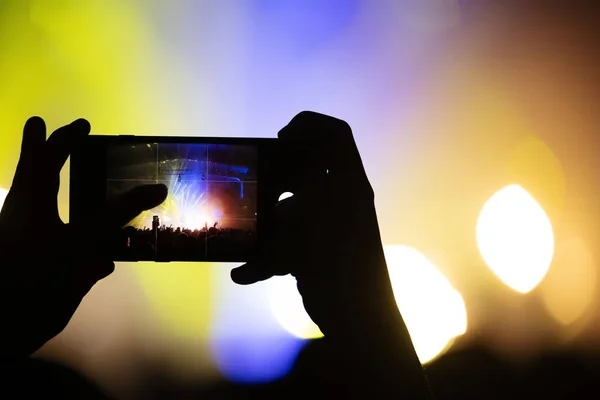 smartphone screen in the hand of a fan shooting video and photos at a concert of your favorite band. festival atmosphere