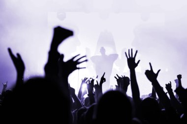 Sahnedeki bir müzik grubundan bir sanatçının silueti ve bir konserdeki kalabalığın elleri. Festival posteri. Görüntü. Seçici odak