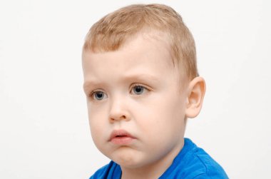 Beyaz bir arka planda mavi tişörtlü tombul yanaklı çocuk. Şaşırmış bebek