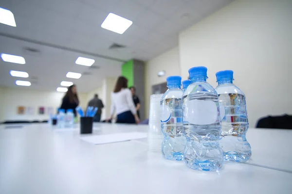 Ofisteki toplantı salonunda iş arkadaşlarının toplantısı için bir şişe içme suyu ve plastik bardak. Seminer ya da eğitim. kurumsal konferans ve iş eğitimi