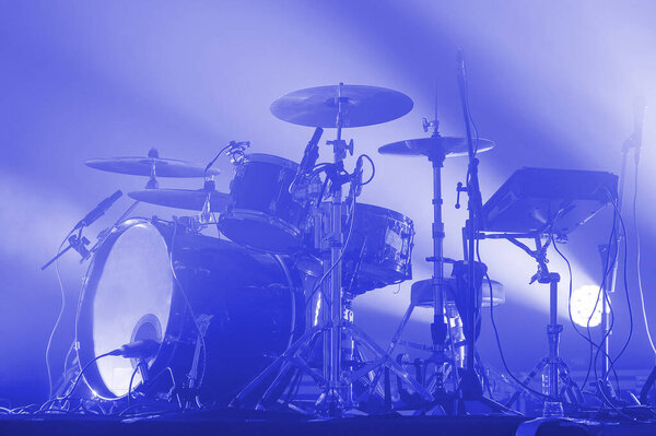 современная барабанная установка рок-группы на сцене в синем свете. концертный зал. Плакат музыкального фестиваля
