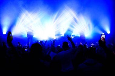 Konserdeki kalabalığın sahne ışıkları altında sahnenin bulanık görüntüsü