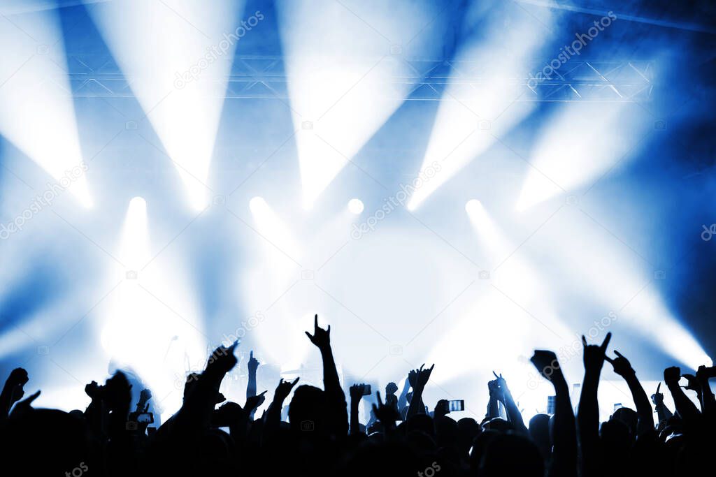 applauding crowd in front of the stage at a music festival in the light of spotlights