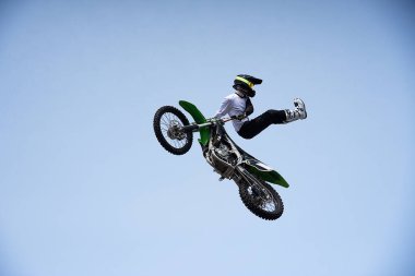 Kasklı bir sürücü motosikletle havada riskli bir sıçrama yapar. Motokros yarışması. Tehlikeli dublörler Nf motosikletçiler gökyüzü arka planı karşı.