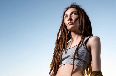 Kısa bluzlu ve günbatımında modaya uygun kot giyen ince saçlı kız. Güneş ışınları ve güzel bir kız. moda