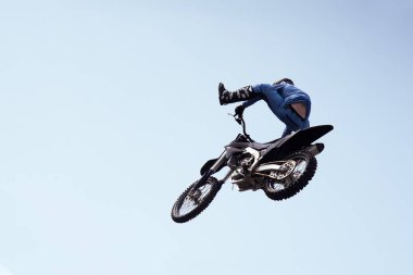Kasklı bir sürücü motosiklet üzerinde havada riskli bir gösteri sergiliyor. Motokros yarışması. Tehlikeli motosiklet dublörleri.