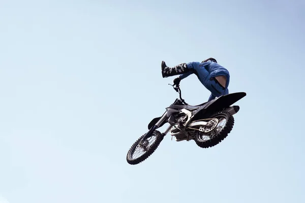 rider in a helmet performs a risky stunt in the air on a motorcycle. motocross competition. dangerous stunts of motorcyclists.