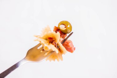 Farfalle makarna güneş ile kurutulmuş domates, jambon ve beyaz zemin üzerine çatal zeytin