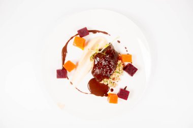 Beyaz zemin üzerine sosu sığır eti yanak sebze, kavrulmuş maydanoz kökü mus, pearl arpa, koyu çikolata ve demi ile şekeri