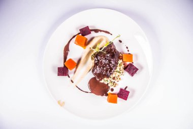 Beyaz zemin üzerine sosu sığır eti yanak sebze, kavrulmuş maydanoz kökü mus, pearl arpa, koyu çikolata ve demi ile şekeri