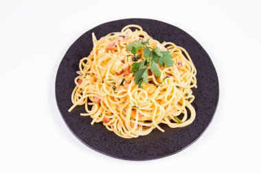 Spagetti Carbonara beyaz bir arka plan üzerinde siyah bir plaka üzerinde bazı maydanoz ile