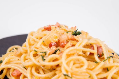 Spagetti Carbonara beyaz bir arka plan üzerinde siyah bir plaka üzerinde bazı maydanoz ile