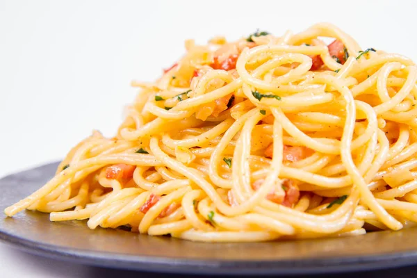 白い背景に黒い皿の上にいくつかのパセリのスパゲティ カルボナーラ — ストック写真