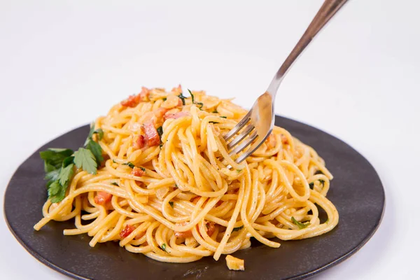 フォークで食べられている白い背景の黒い板にいくつかのパセリのスパゲティ カルボナーラ — ストック写真