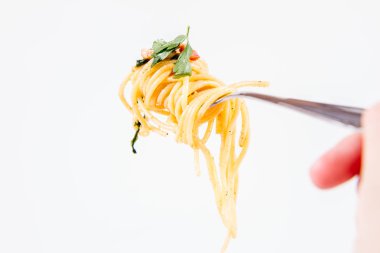 Spagetti Carbonara bazı maydanoz üzerinde bir el tarafından düzenlenen bir çatal ile