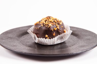 Çikolata ve fındık beyaz bir arka plan üzerinde siyah bir tabakta romlu süslenmiş