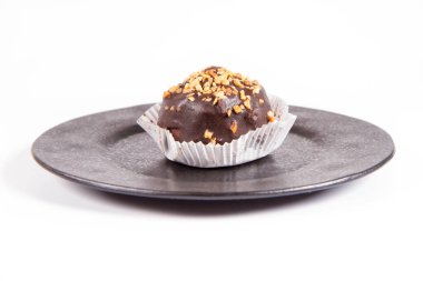 Çikolata ve fındık beyaz bir arka plan üzerinde siyah bir tabakta romlu süslenmiş