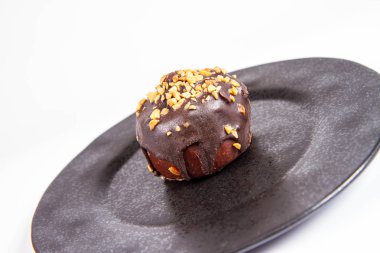 Çikolata ve fındık beyaz bir arka plan üzerinde siyah bir tabakta romlu süslenmiş