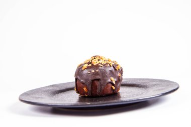 Çikolata ve fındık beyaz bir arka plan üzerinde siyah bir tabakta romlu süslenmiş
