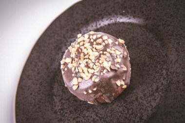 Çikolata ve fındık beyaz bir arka plan üzerinde siyah bir tabakta romlu süslenmiş