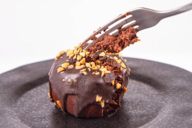 Çikolata ve fındık beyaz zemin üzerinde bir çatal ile yenen siyah plaka ile dekore edilmiş romlu