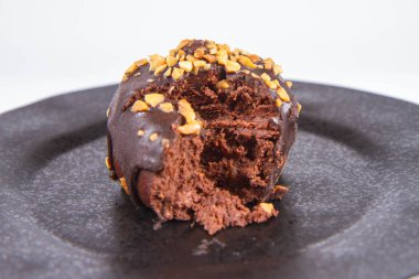 Çikolata ve fındık kısmen yemiş, beyaz bir arka plan üzerinde siyah bir plaka üzerinde romlu süslenmiş