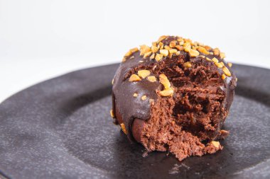 Çikolata ve fındık kısmen yemiş, beyaz bir arka plan üzerinde siyah bir plaka üzerinde romlu süslenmiş