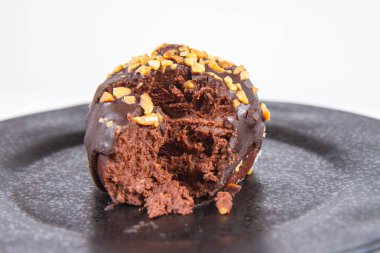 Çikolata ve fındık kısmen yemiş, beyaz bir arka plan üzerinde siyah bir plaka üzerinde romlu süslenmiş
