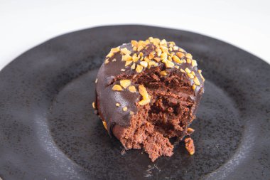 Çikolata ve fındık kısmen yemiş, beyaz bir arka plan üzerinde siyah bir plaka üzerinde romlu süslenmiş