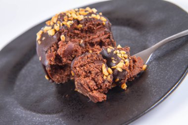 Çikolata ve fındık beyaz zemin üzerinde bir çatal ile yenen siyah plaka ile dekore edilmiş romlu